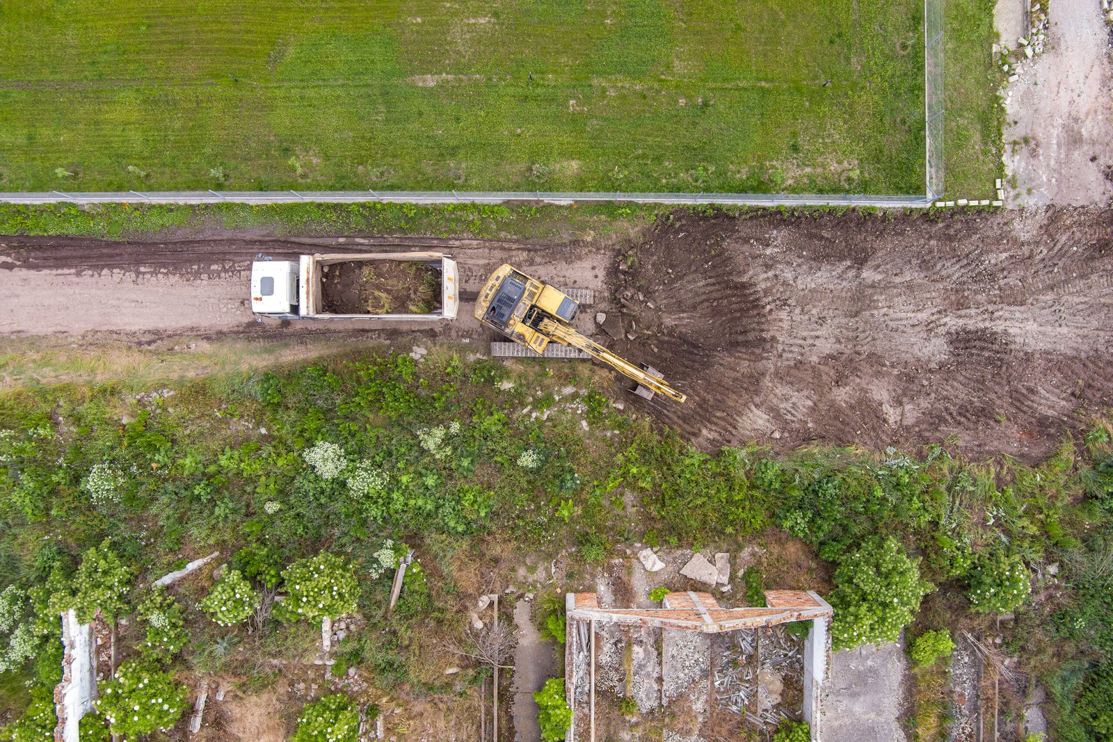 Aerial view of an excavator working removing earth Aerial view of an excavator working removing earth and loading it into a truck dumper on a construction site.