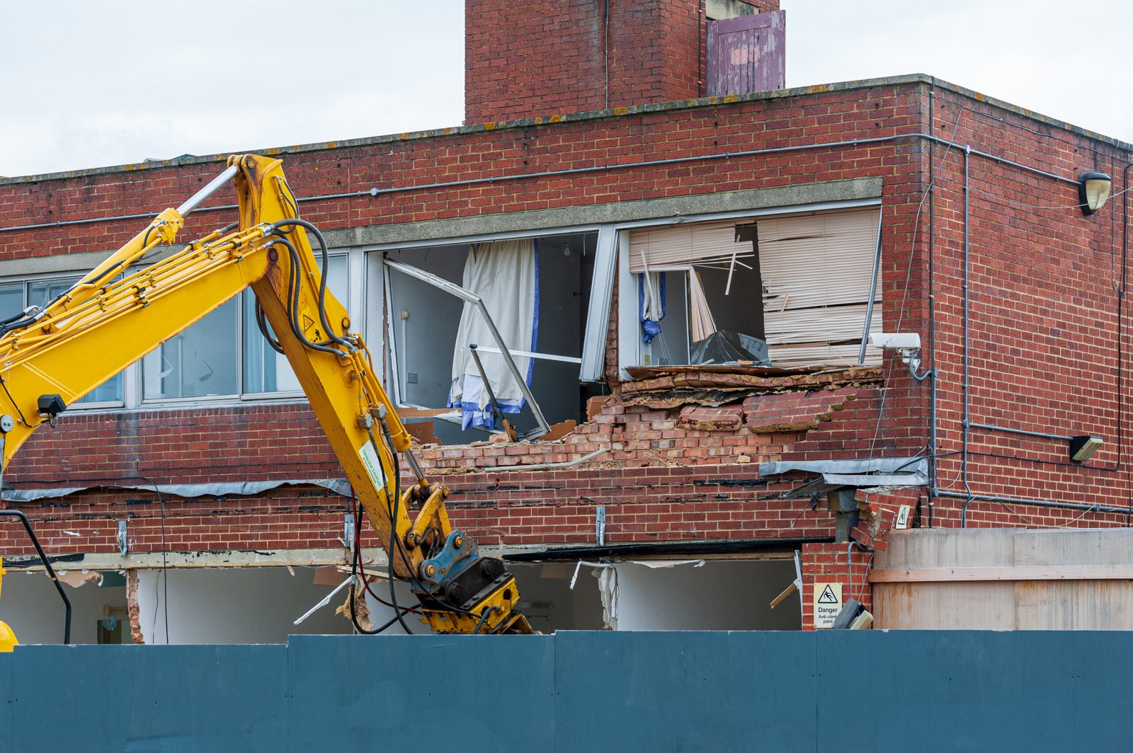 Demolition of an old building with a long reach machine hydraulic jaw. Demolition of an old building with a long reach machine hydraulic jaw. Regeneration of a space for new, modern building.